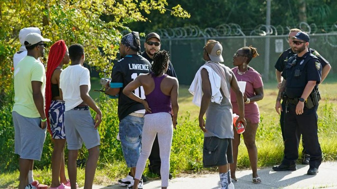 Locals talk with Jacksonville police after three people were killed in a Dollar Store shooting. Photo / AP