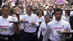Waiters and waitresses carry trays with a cup of coffee, a croissant and a glass of water as they take part in a 2km waiter's run through the streets of Paris. Photo / AP