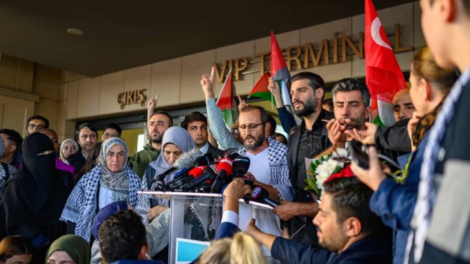 Turkish activist Halil Rifat Canakci (C), one of the activists who were sailing aboard vessels from the Global Sumud Flotilla, speaks to the press after arriving at Istanbul Airport. Photo / Yasin Akgul, AFP