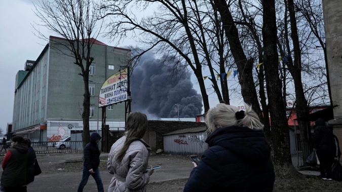 People watch smoke rising behind buildings following explosions in Lviv, western Ukraine yesterday. Photo / AP