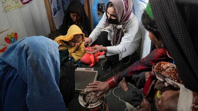 A nurse checks the weight of a child in the makeshift clinic organised by World Vision. (Photo / AP)