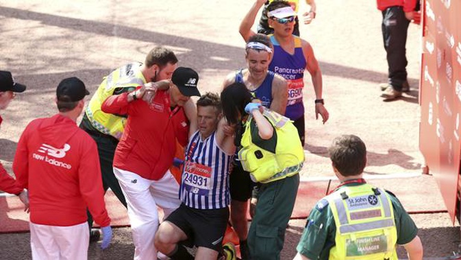 A runner is helped by medical staff after crossing the finish line during the 2018 Virgin Money London Marathon, Sunday April 22, 2018. (Photo / AP)