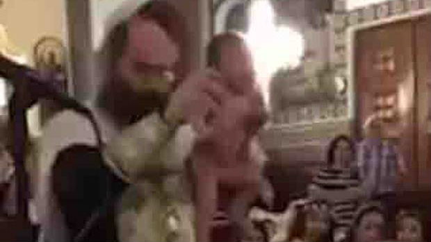 Greek Orthodox bishop violently baptising a baby in water. (Source: Youtube / @Alex Alexioy)