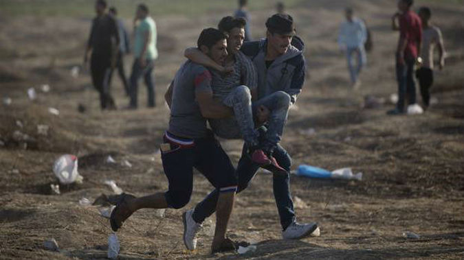 Palestinian protesters carry a wounded man shot by Israeli troops during a protest at the Gaza Strip's border. (Photo / AP)