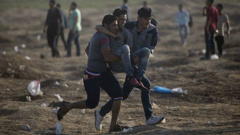 Palestinian protesters carry a wounded man shot by Israeli troops during a protest at the Gaza Strip's border. (Photo / AP)