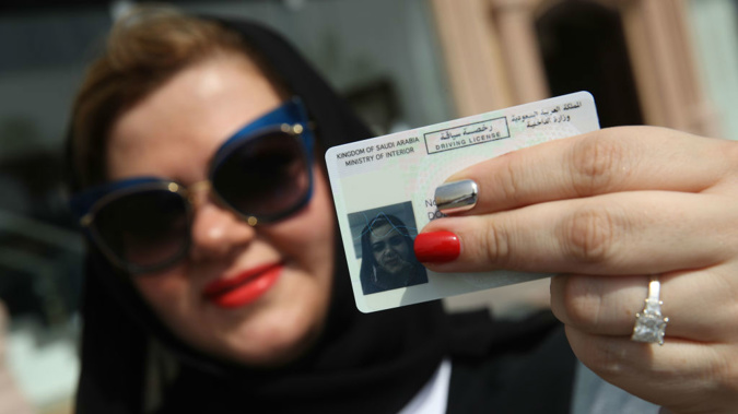 A Saudi woman holds up her drivers license on the first day women are allowed to legally drive. (Photo / Getty Images)
