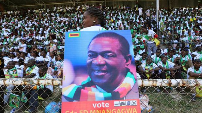 Supporters of Zimbabwean President Emmerson Mnangagwa, portrait on placard, attend an elections rally in Hwange. Photo / AP