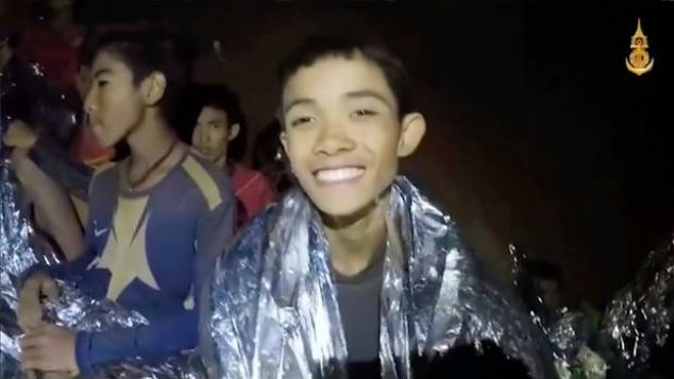 A Thai boy smiles as Thai Navy SEAL medic help injured children inside a cave in Mae Sai northern Thailand. Photo / AP
