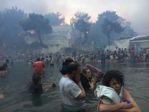 People escaping wildfires wade into the waters of the 'Silver Coast' beach in Mati, Greece. (Photo / AP)
