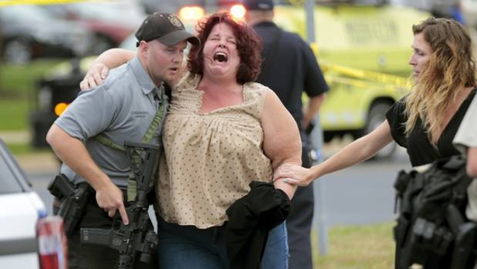 A woman is escorted from the scene of a shooting at a software company in Wisconsin where four people were wounded. The gunman was killed by police. Photo / AP