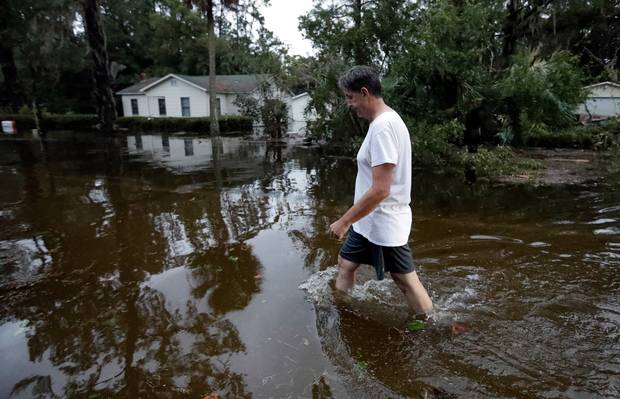 John Gouge walks through flood waters as he goes to check on the post office in St Marks, Florida. Photo / AP