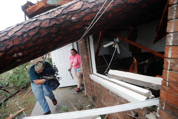 Megan Williams, left, and roommate Kaylee O'Brian take belongings from their destroyed home after several trees fell on the house during Hurricane Michael in Panama City, Florida. Photo / AP