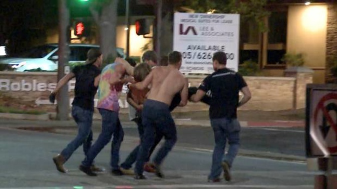 A victim is carried from the scene of a shooting after a gunman opened fire in a bar killing 12 people. Photo / AP
