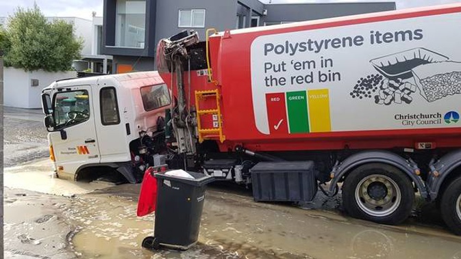 A Waste Management rubbish truck after it plunged into a Christchurch sinkhole caused by a burst water main this morning. (Photo / Matthew Ryley)
