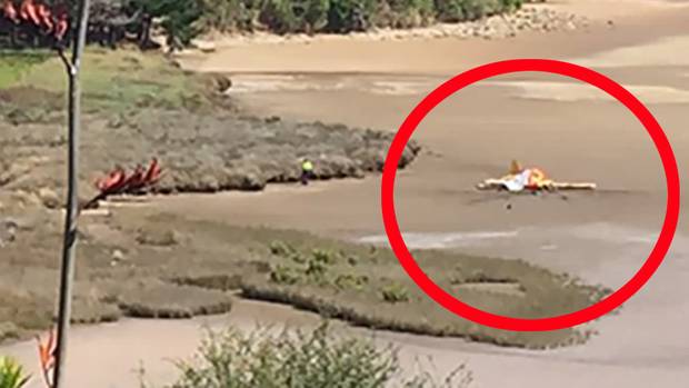 The light aircraft is covered with a tarpaulin as emergency services attend the scene. (Photo / Belinda Feek)