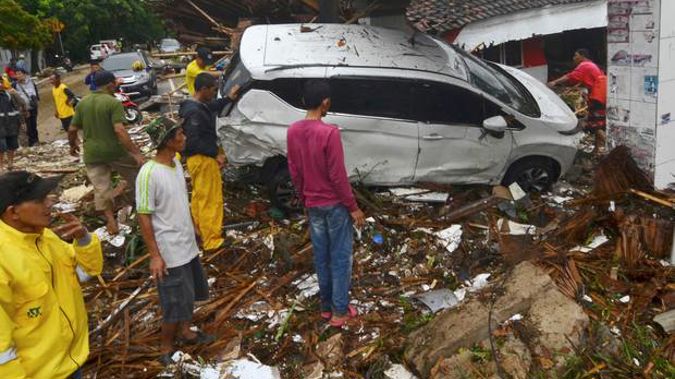 People inspect the wreckage of a car swept away by a tsunami in Carita, Indonesia. Photo / AP