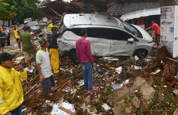 People inspect the wreckage of a car swept away by a tsunami in Carita, Indonesia. Photo / AP