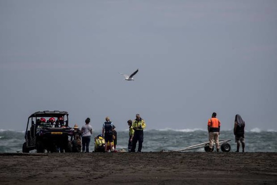 Family and emergency services wait at the shoreline at Whatipu Beach after a boy was swept away. (Photo / Michael Craig)