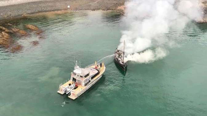 Police fight the fire on the boat. (Photo / Auckland Rescue Helicopter Trust)
