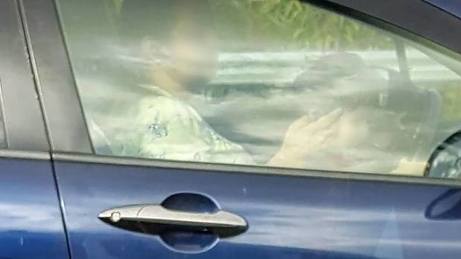 A child sitting on the lap of a woman texting while driving on the Southern Motorway. Photo / Supplied