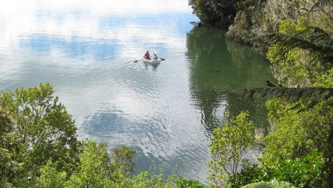 Rowers paddle near one of New Zealand's most remote holiday homes now up for sale on Stewart Island. (Photo / Supplied)