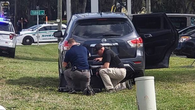 Law enforcement officials take cover outside a SunTrust Bank branch after a man fired shots inside. Photo / AP