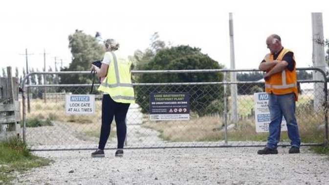 A WorkSafe NZ official, watched by another official examines the gate through which a 3-year-old is thought to have passed before drowning. Photo / Giordano Stolley