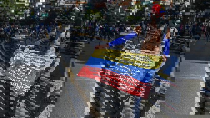 A demonstrator seen holding the Venezuelan flag while wearing a gas mask during a demonstration against President Nicolas Maduro's policies. Photo / Getty Images