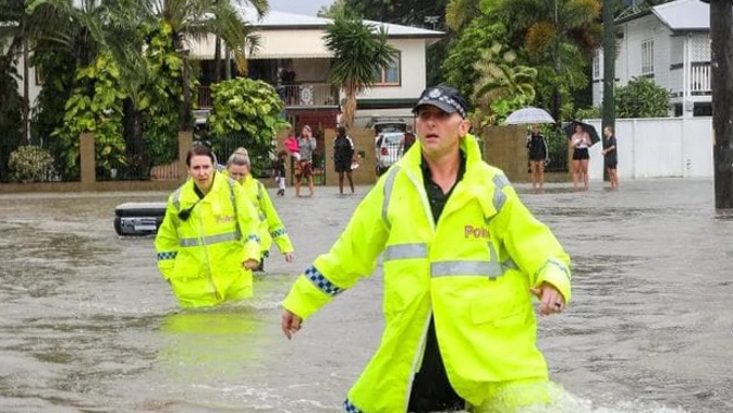 Senior Constable Wade Jackson leads police through flooded water in Hermit Park to assist residents to safely get out. Photo / News Corp Australia/Supplied