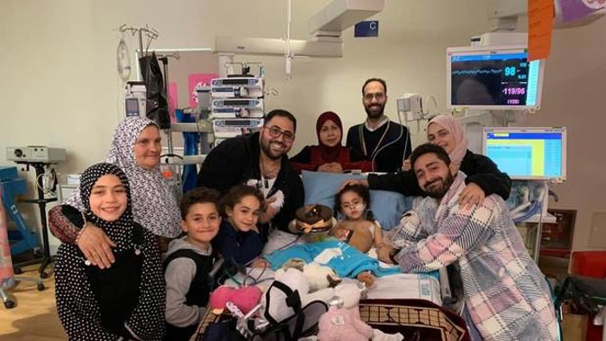 Mosque shooting survivor Alen Alsati is surrounded by family and friends in Starship hospital after waking from a coma. Her father Wasseim Alsati (right) was also injured. (Photo / Supplied)