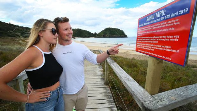 Visitors Kate Wardlaw from Taupo and Adam Howie from the United Kingdom reading one of the signs posted along Matapouri beach. Photo/Tania Whyte