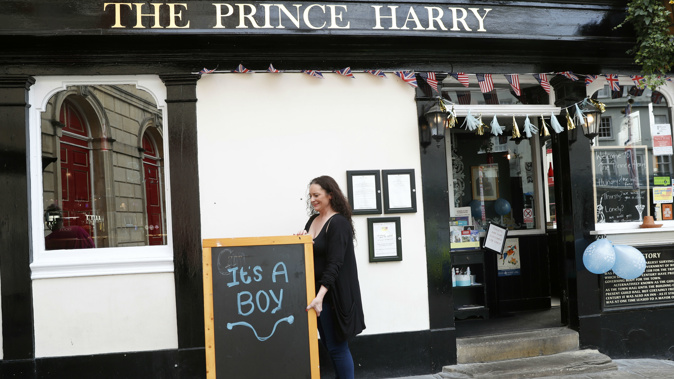 A woman at the 'Prince Harry' puts out a sign celebrating the birth. (Photo / AP)