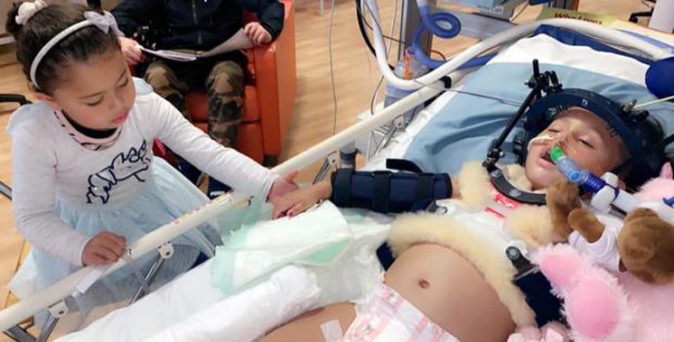 Two-year-old Amirah Najim-Phillips in Starship ICU, holding hands with her elder sister Zahara. Photo / Supplied