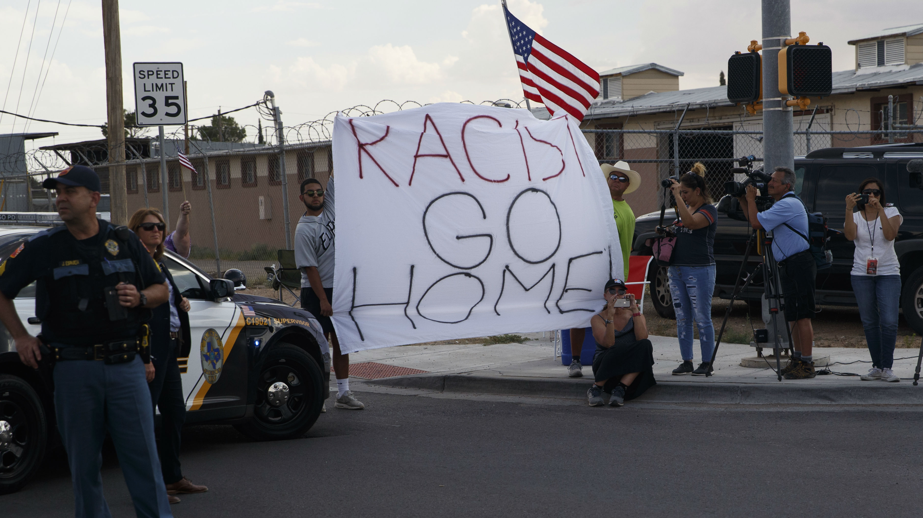 Demonstrators hold a sign as the motorcade carrying President Donald Trump arrives to visit a joint operations center to meet with first responders after the El Paso mass shooting. (Photo / AP)