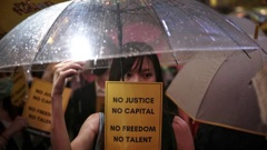 A woman holds an umbrella and a placard as people gather at Chater Garden to give support to the recent protests against the extradition bill, at the financial district in Hong Kong. Photo / AP