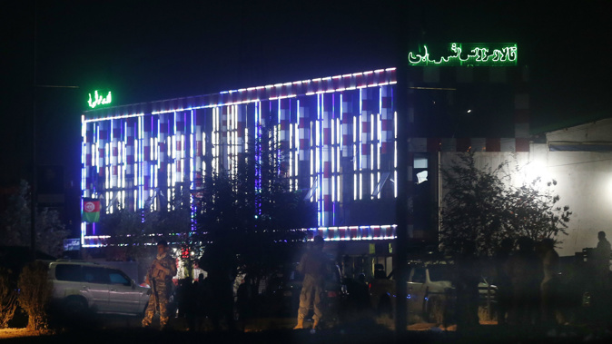 Afghan police men stand guard outside the wedding hall after an explosion in Kabul