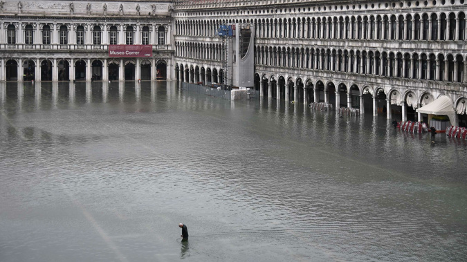 A man crosses the flooded St. Mark's Square after an exceptional overnight high tide on November 13. (Photo / AFP via CNN)