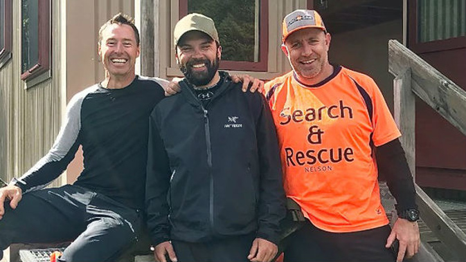 US tramper Chris Muse (centre) with rescuers Dwayne and Kris at Red Hills Hut. Muse activated a personal locator beacon after being swept away in a swollen river. Photo / Supplied
