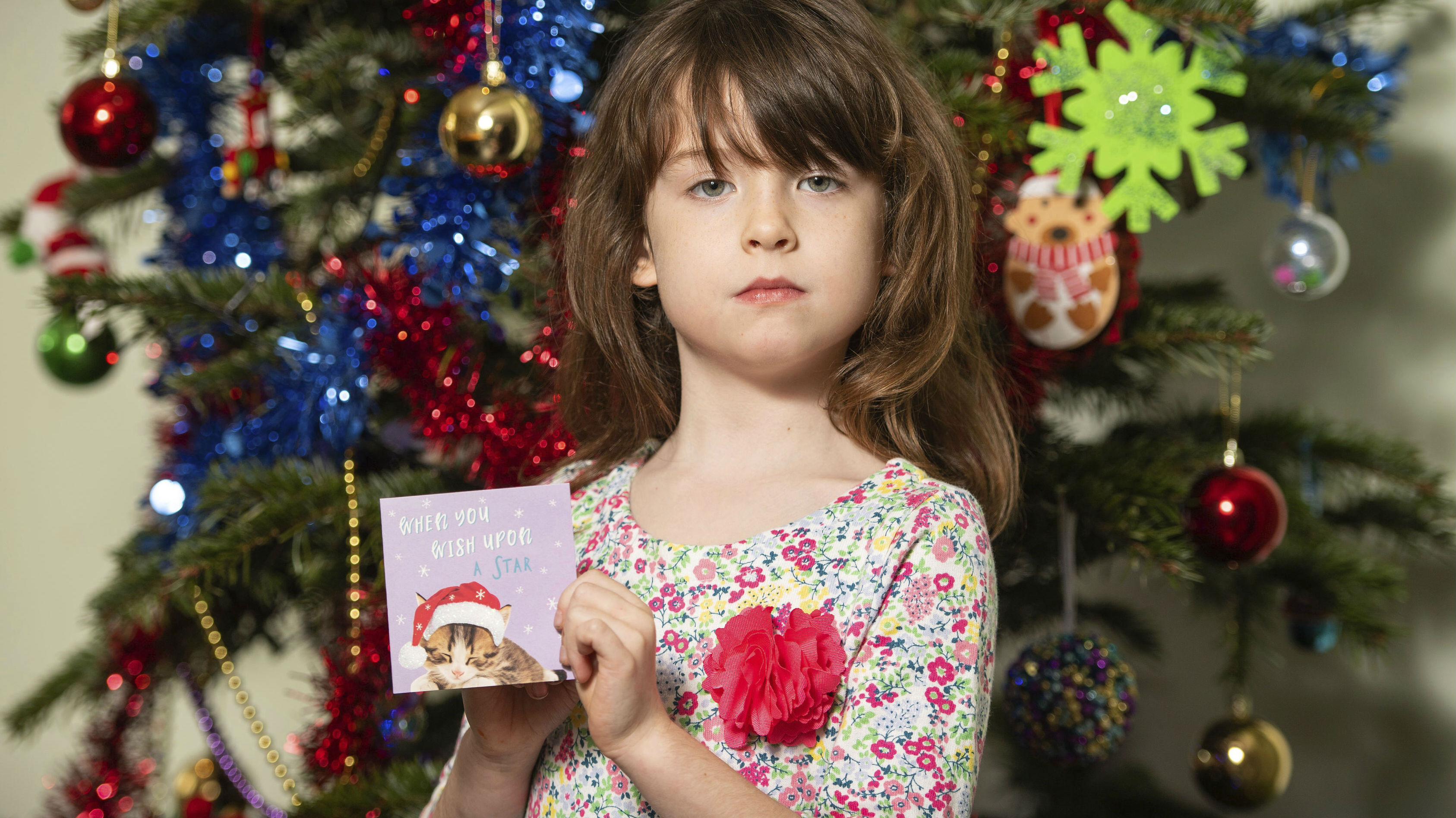 Florence Widdicombe, 6, poses with a Tesco Christmas card from the same pack as a card she found containing a message from a Chinese prisoner. (Photo / AP)