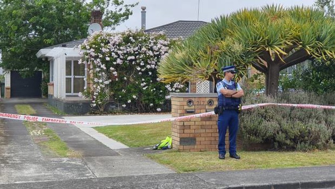 A police officer stands guard outside a house on Sunnyside Cres, Papatoetoe, this afternoon. Photo / Visual Media Productions