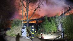 Firefighters stand in front of the burning monkey house at Krefeld Zoo. (Photo / AP)