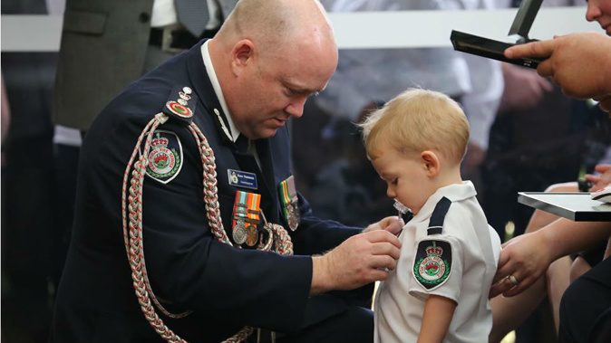 Commissioner Shane Fitzsimmons presents the medal to Geoffrey Keaton's son, Harvey. (Photo / NSW Rural Fire Service - Facebook)