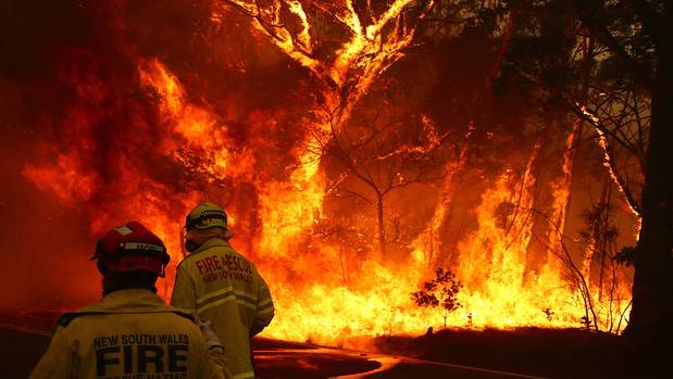 Fire and Rescue personnel run to move their truck as a bushfire burns next to a major road and homes on the outskirts of the town of Bilpin near Sydney on December 19. Photo / Getty
