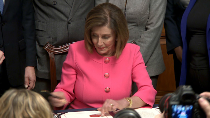 ancy Pelosi signs the articles of impeachment against President Trump. (Photo / CNN)