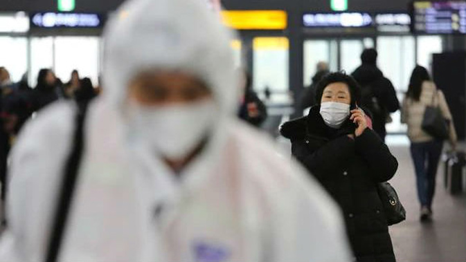 A woman wears a mask as an employee works to prevent a new coronavirus at Suseo Station in Seoul, South Korea. (Photo / AP)