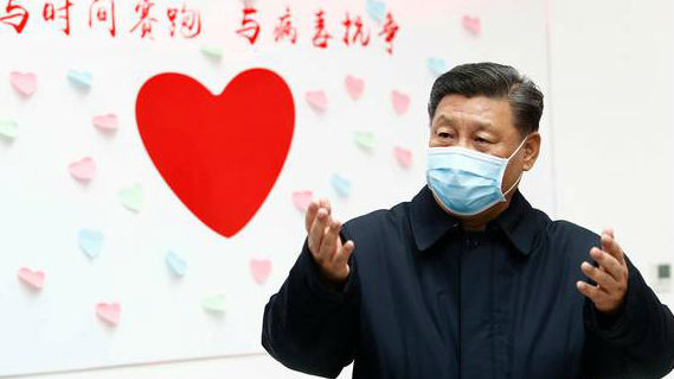 Chinese President Xi Jinping gestures near a heart shape sign and the slogan 'Race against time, Fight the Virus' on February 10. (Photo / AP)