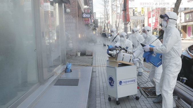 Workers wearing protective gears spray disinfectant as a precaution against the coronavirus at a shopping street in Seoul, South Korea. (Photo / AP)