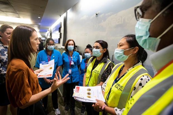 Prime Minister Jacinda Ardren speaks to masked health officials in the customs hall at Auckland International Airport. Photo / File