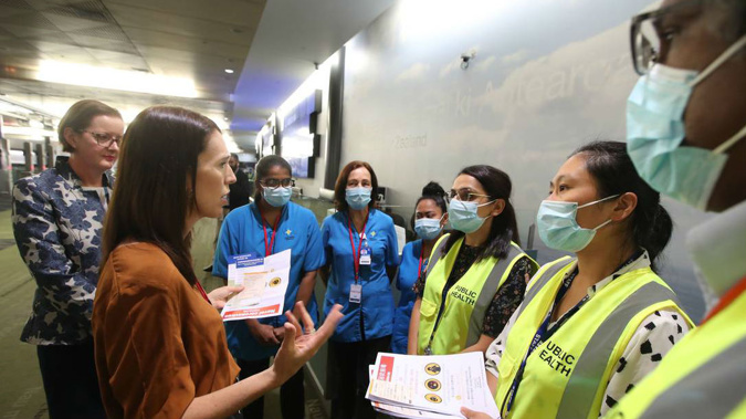 Jacinda Ardern talking with health officials at Auckland Airport. (Photo / NZ Herald)