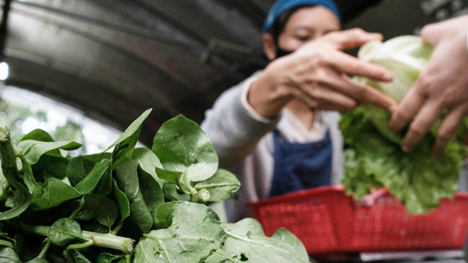 A woman wearing a facemask sells vegetables at a community farm in Hong Kong on March 18. (Photo / Getty)